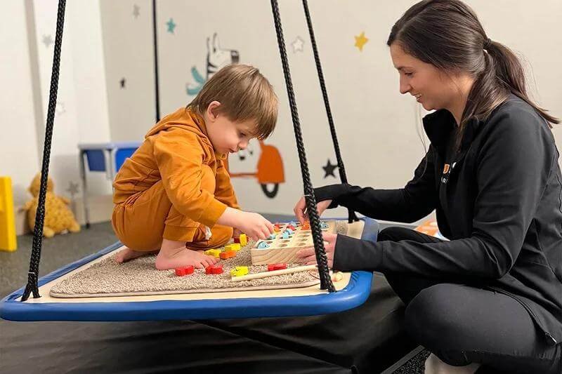 Occupational Therapist supporting an autistic child during a sensory activity